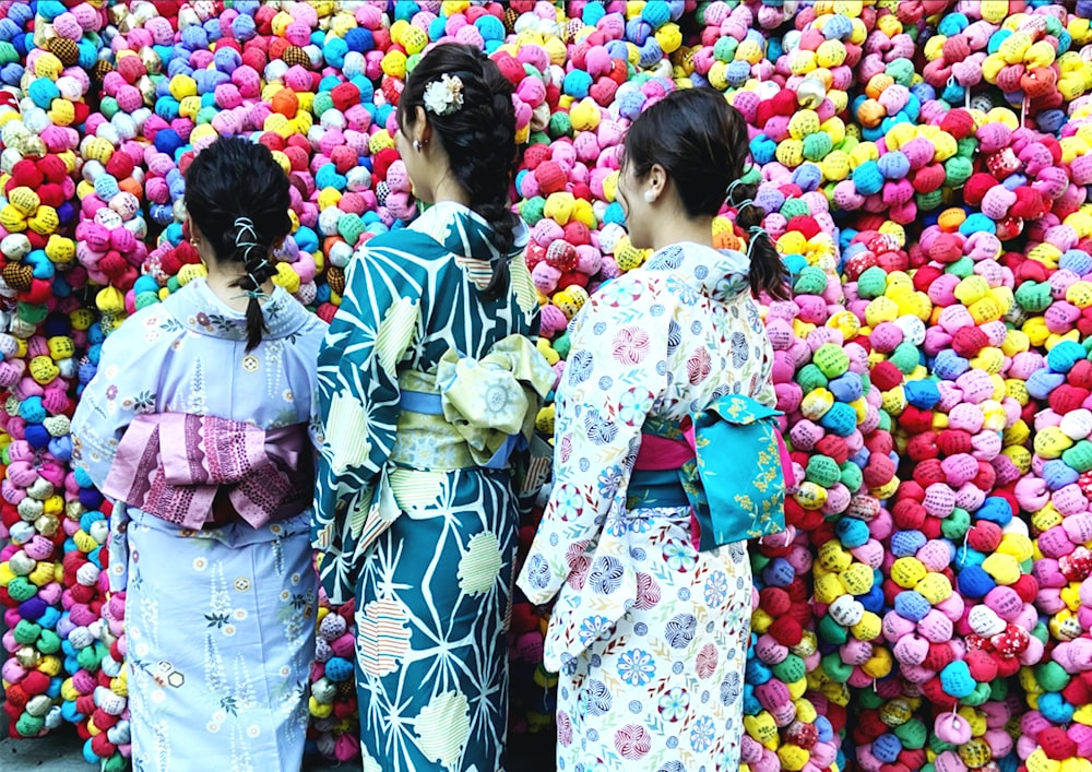 2 mulheres em quimono branco e azul em pé ao lado de balões multicoloridos