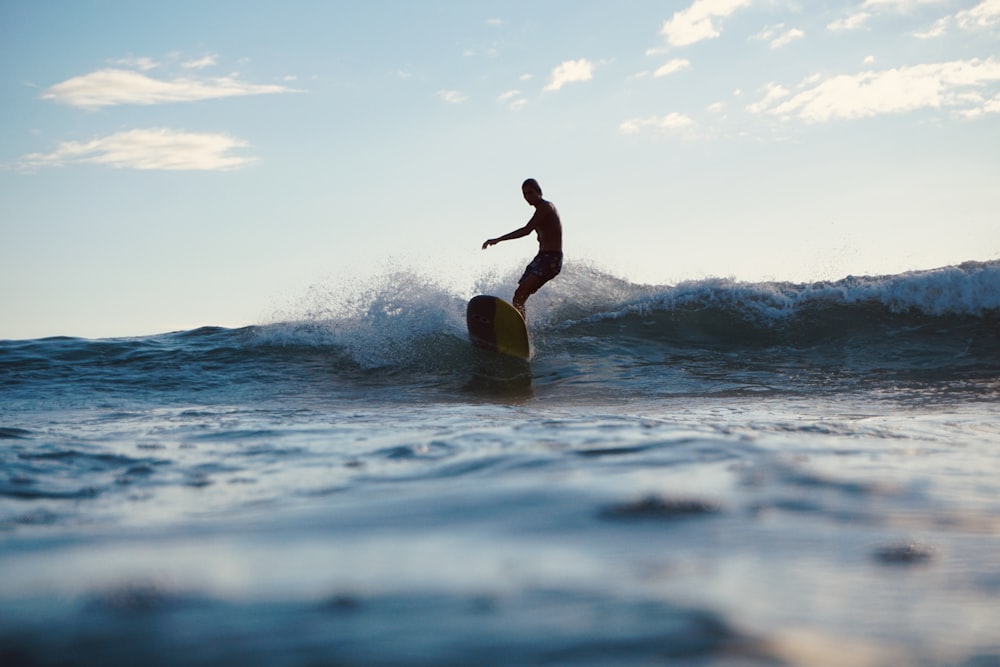 woman in black wetsuit surfing on sea waves during daytime