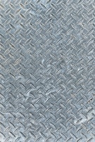 An industrial metal surface with a raised diamond plate pattern, often used for traction and durability. The surface appears weathered with slight discoloration and scuff marks.