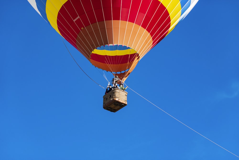 red yellow and blue hot air balloon in mid air under blue sky during daytime