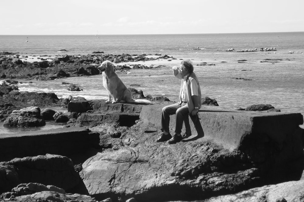 woman in white tank top and black pants standing on rock near sea