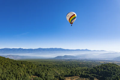 A colorful hot air balloon floating gently over alpine mountains at sunrise.