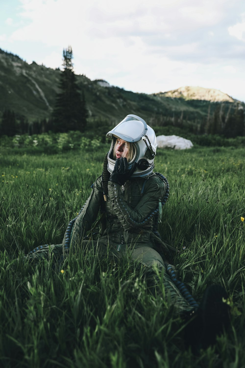 man in black jacket wearing white helmet sitting on green grass field during daytime