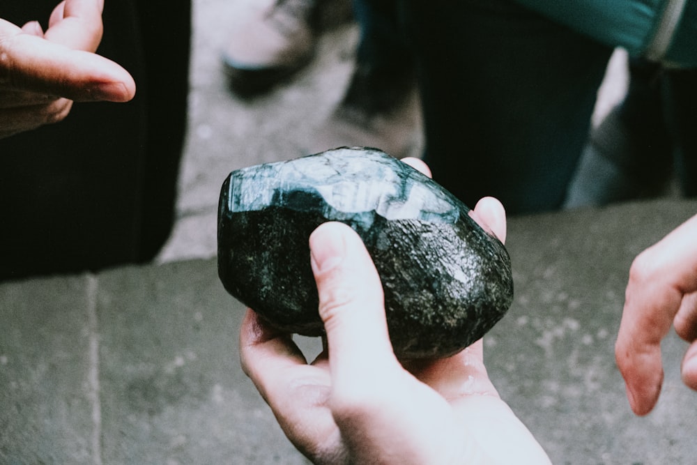 person holding black stone fragment