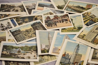 A collection of vintage postcards featuring various cityscapes and landmarks, arranged in an overlapping manner. The postcards depict historical buildings, urban scenes, and architectural landmarks from different perspectives.