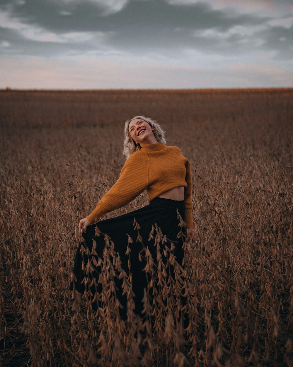 woman in brown long sleeve shirt and black and white floral skirt standing on brown grass