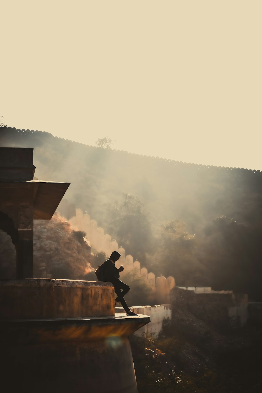 man sitting on brown wooden bench looking at the fog