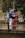 man in blue jacket and woman in red dress standing on brown wooden fence during daytime