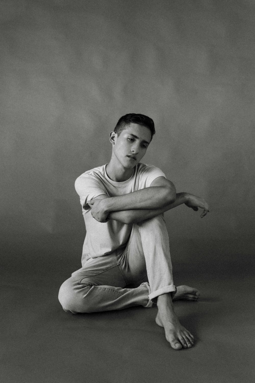 man in white tank top and pants sitting on floor