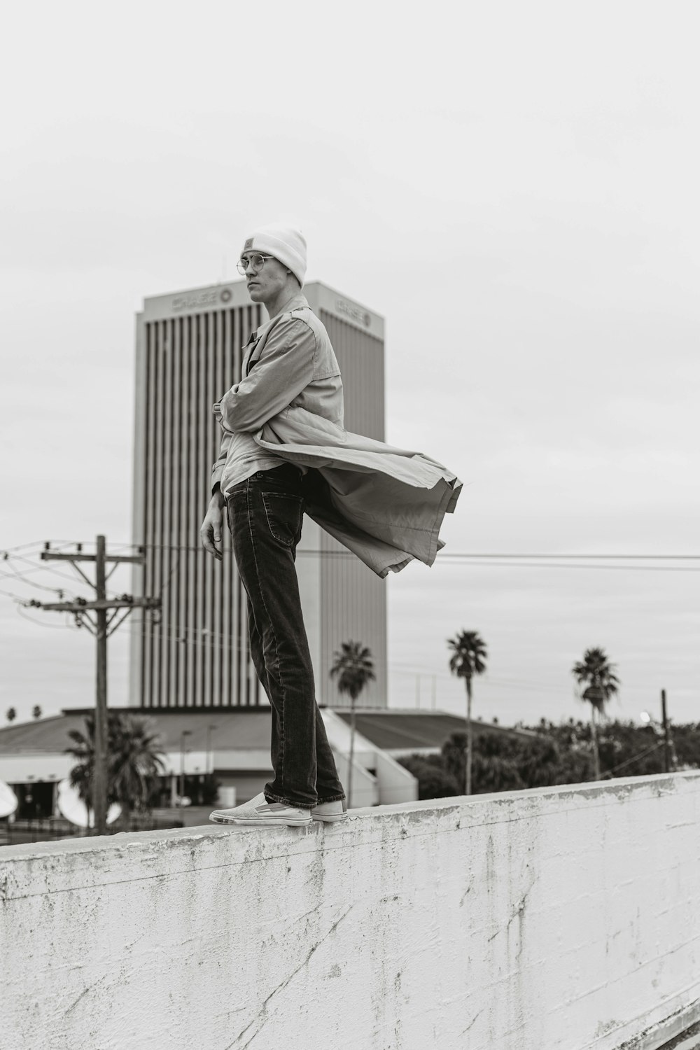 man in white long sleeve shirt and black pants standing on white concrete wall during daytime