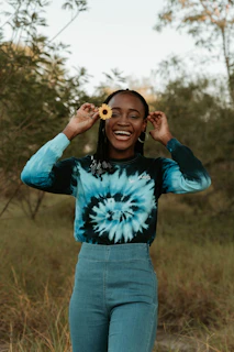 A smiling customer wearing a custom sublimation t-shirt with wild lovebug designs in a sunlit garden