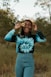 woman in blue and white long sleeve shirt standing on brown grass field during daytime