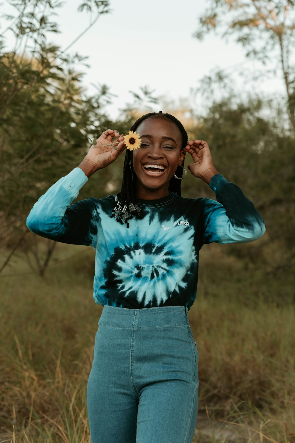 mulher na camisa de manga comprida azul e branca em pé no campo de grama marrom durante o dia