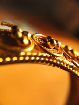 Close-up of a gleaming gold 3D printer crafting a delicate jewelry piece.