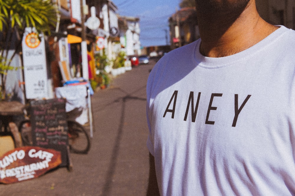 man in white and blue crew neck t-shirt standing on street during daytime