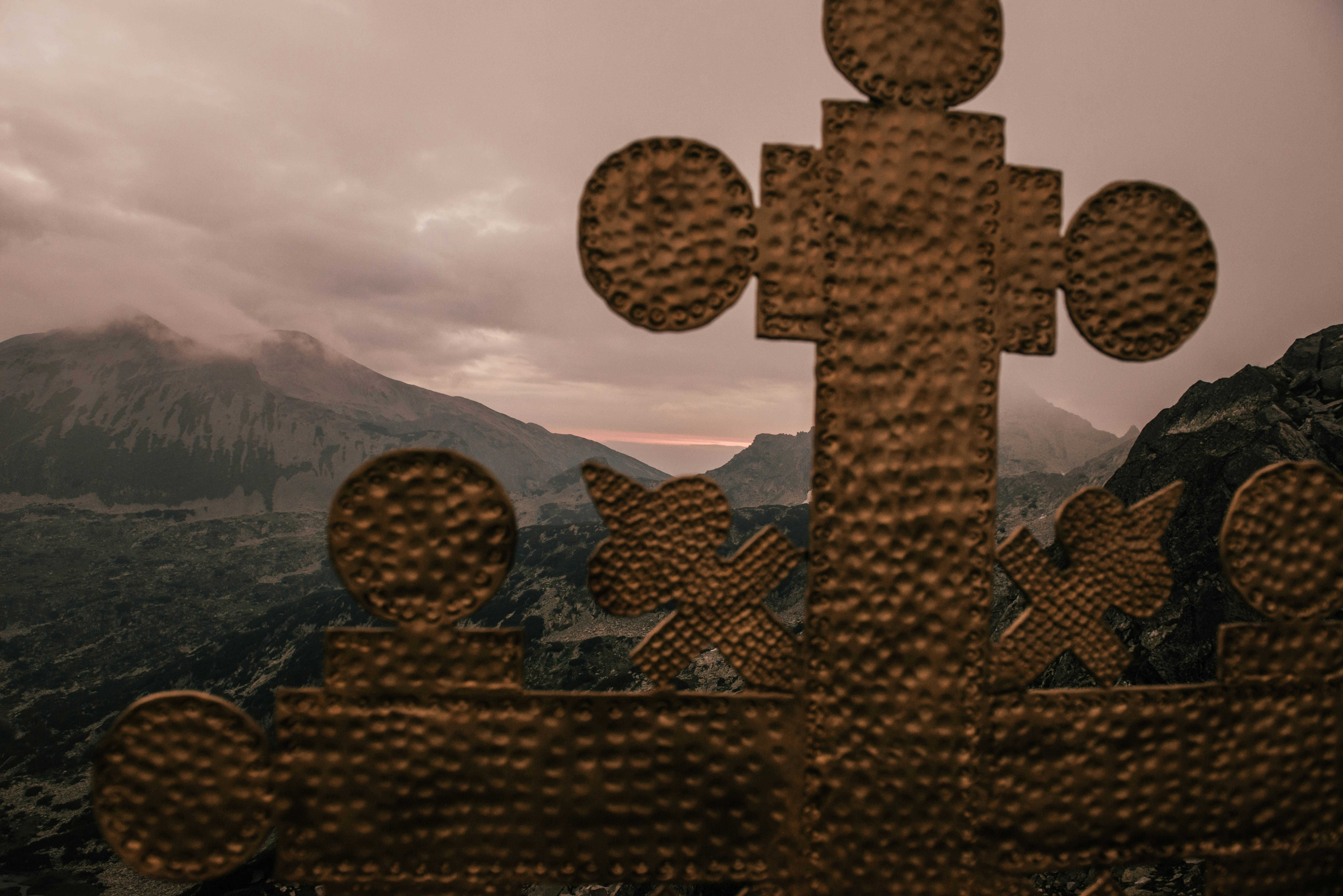 brown concrete cross on top of mountain during daytime