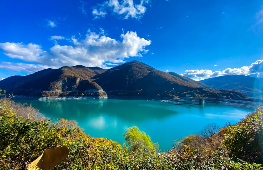 See umgeben von grünen Bäumen und Bergen unter blauem Himmel tagsüber