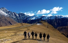 group of people standing on brown field near snow covered mountain during daytime