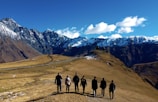 group of people standing on brown field near snow covered mountain during daytime