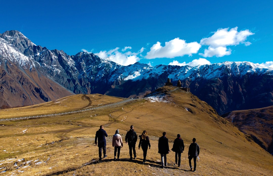 group of people standing on brown field near snow covered mountain during daytime,