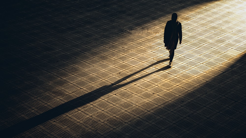 man in black jacket walking on brown brick floor