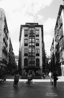 grayscale photo of people walking on street near building
