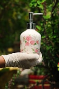 person holding white and pink floral pump bottle