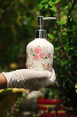 person holding white and pink floral pump bottle