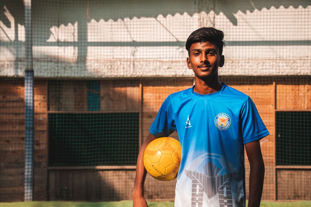 man in blue nike soccer jersey holding yellow soccer ball