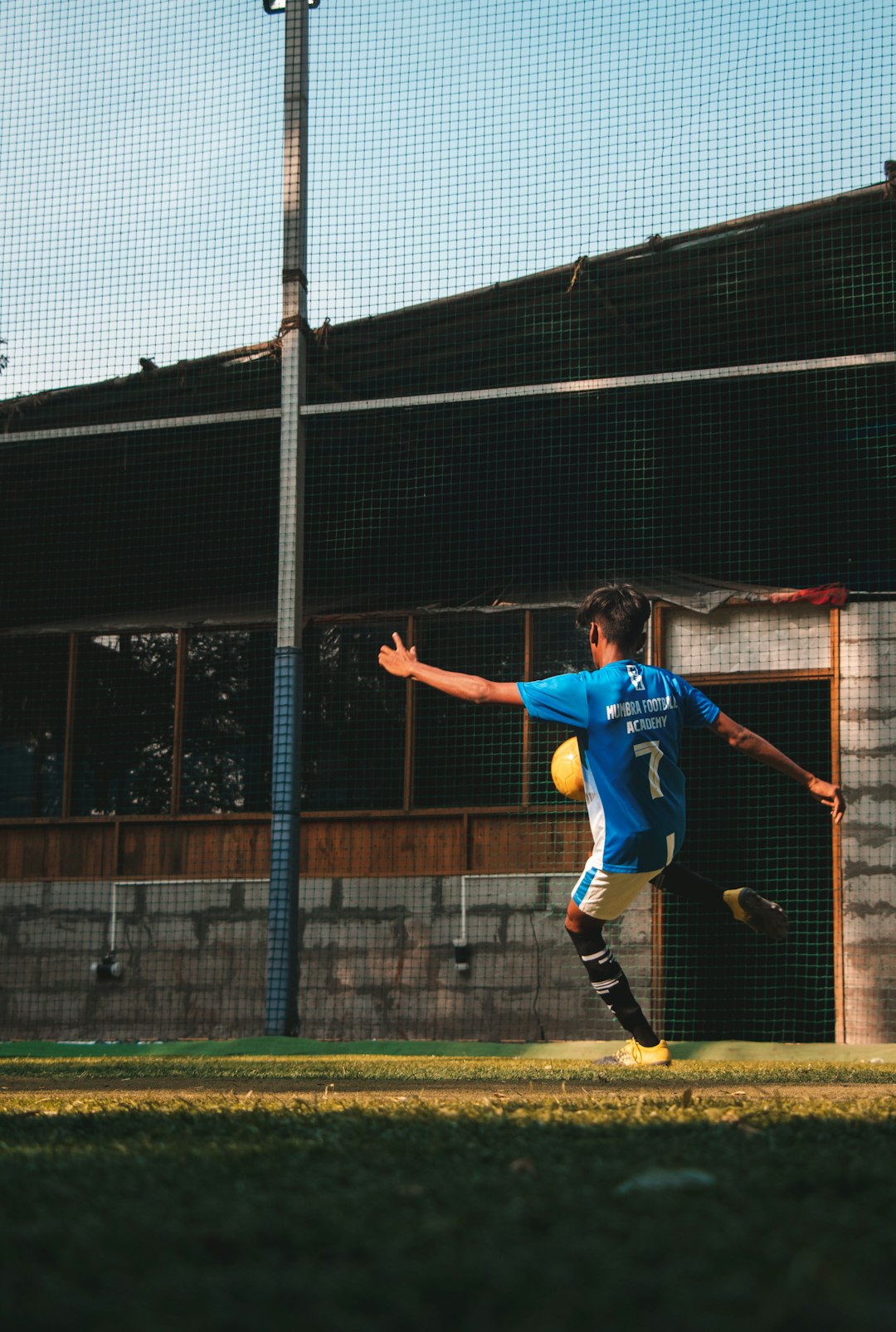 man in blue soccer jersey kicking ball during daytime