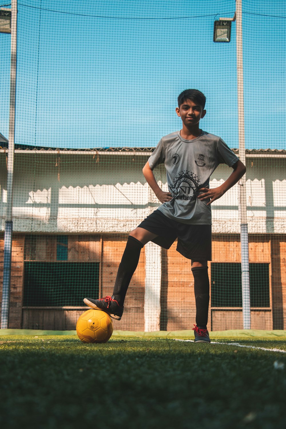 man in black and white tank top and brown pants playing soccer during daytime