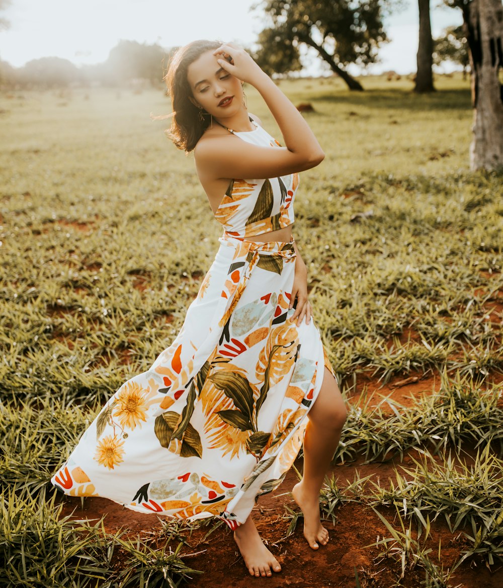 woman in orange and white floral dress sitting on grass field