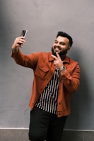 woman in brown coat standing beside red wall