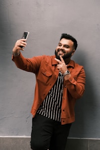 woman in brown coat standing beside red wall