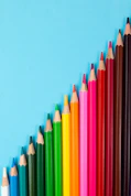 stylized diamond shape with colored pencils lined up in a row on a blue background