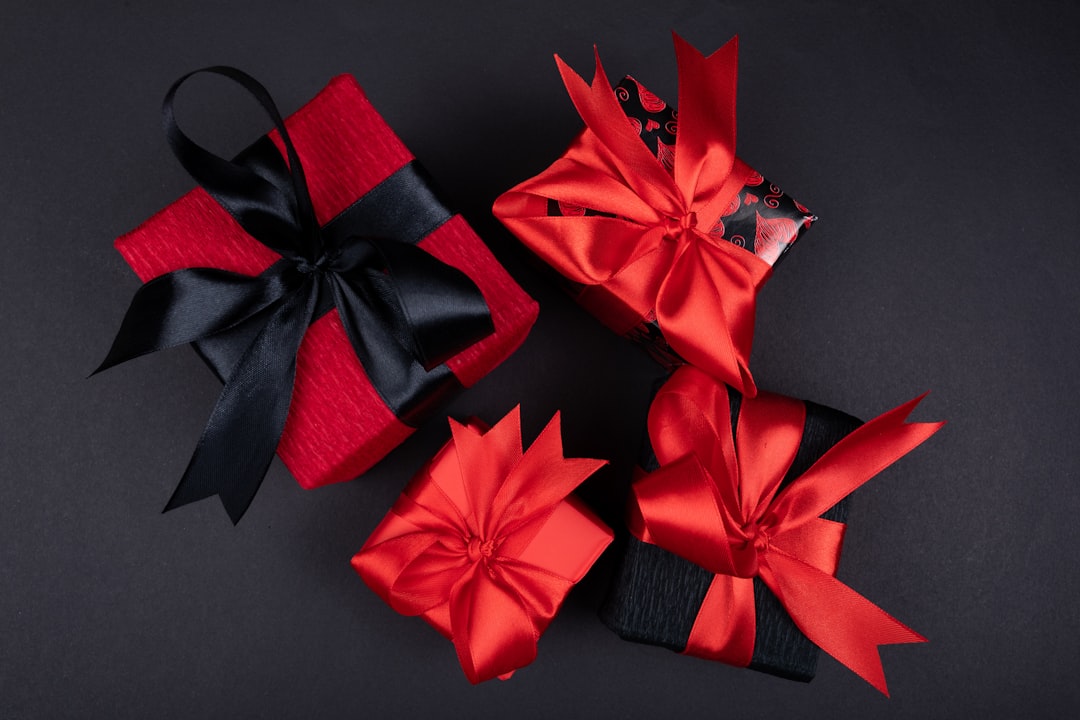 red ribbon on black textile, Red and black gift box on black background