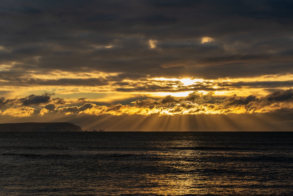 body of water under cloudy sky during sunset