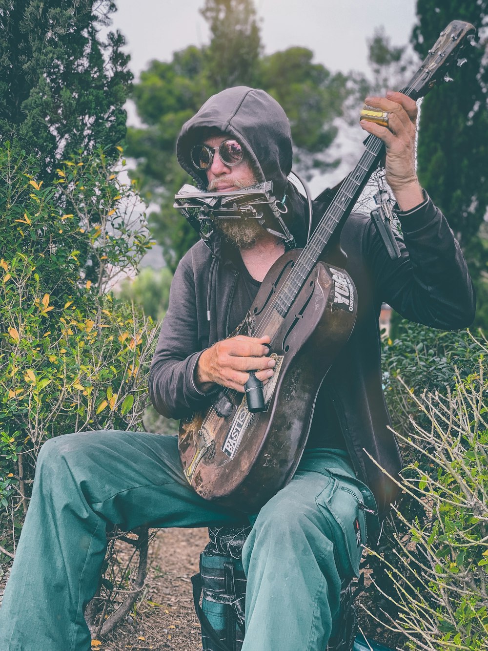 man in black leather jacket playing brown acoustic guitar