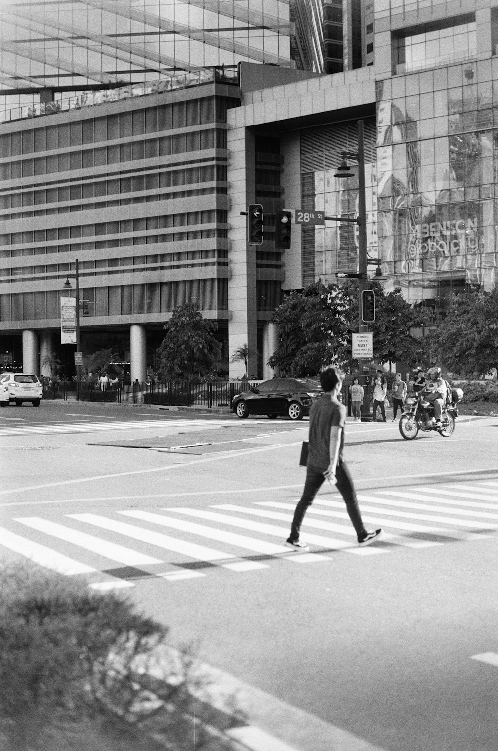 man in black jacket and pants walking on pedestrian lane in grayscale photography
