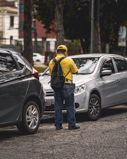 man in yellow hard hat standing beside black suv during daytime