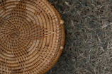 Textured shot of a handwoven basket resting on a wooden shelf.