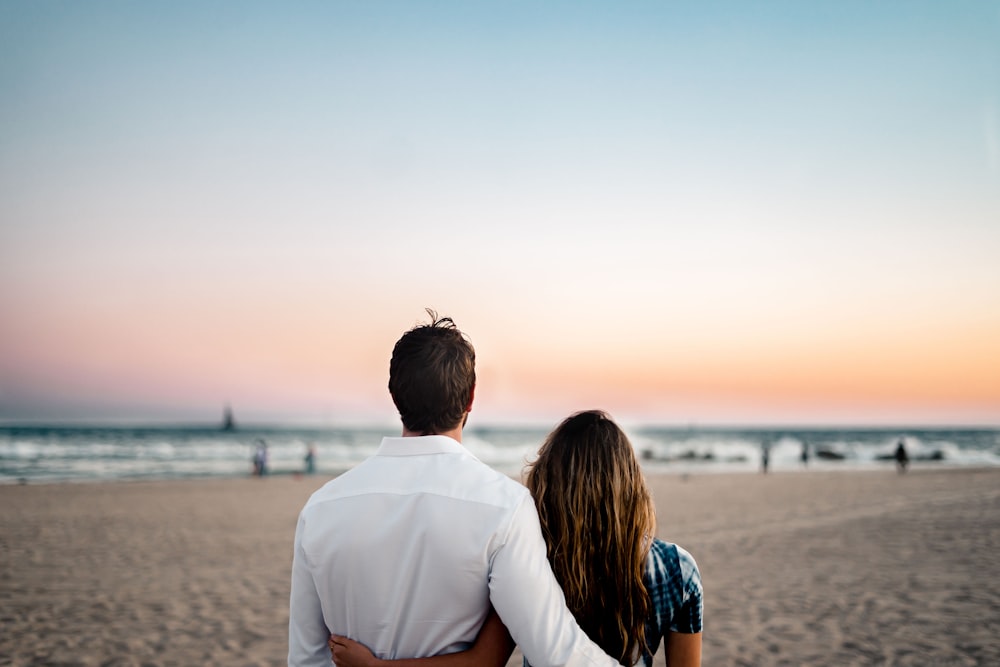 man and woman standing on brown sand during daytime