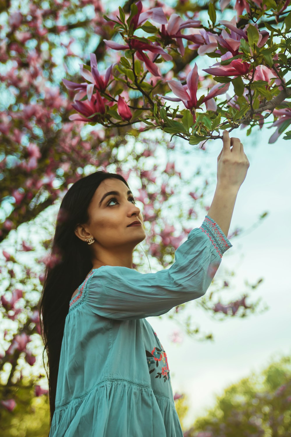 woman in blue long sleeve shirt holding purple flowers