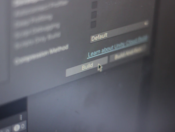 A close-up view of a computer screen displaying software development settings with options like 'Default' and 'Build' visible. A cursor hovers over the 'Build' button, suggesting interaction.