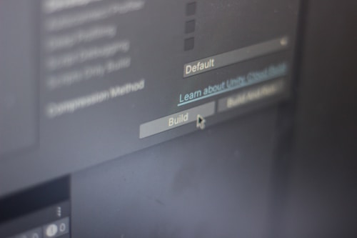 A close-up view of a computer screen displaying software development settings with options like 'Default' and 'Build' visible. A cursor hovers over the 'Build' button, suggesting interaction.