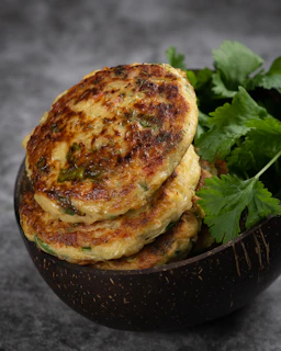 Quinoa patties frying in a pan with golden crust and fresh greens on the side