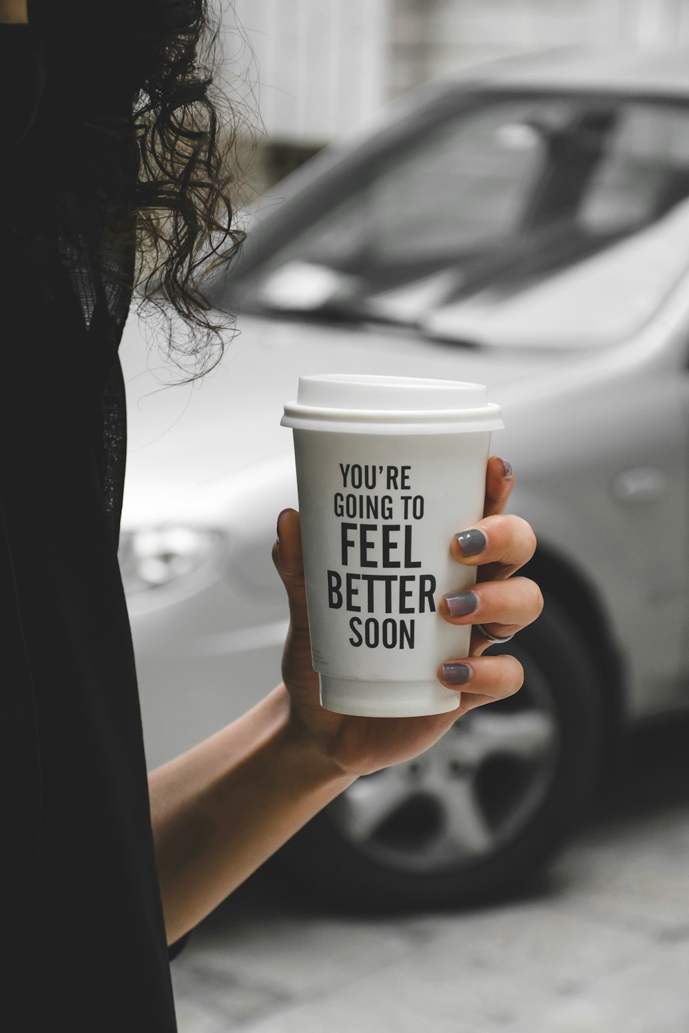 woman holding white and black disposable cup