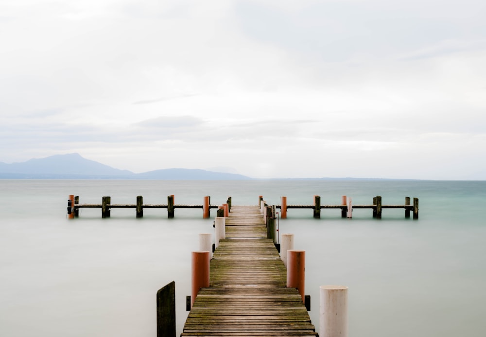 brown wooden dock on sea under white sky during daytime