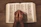 Hands joined in prayer with a softly glowing Bible in the background.