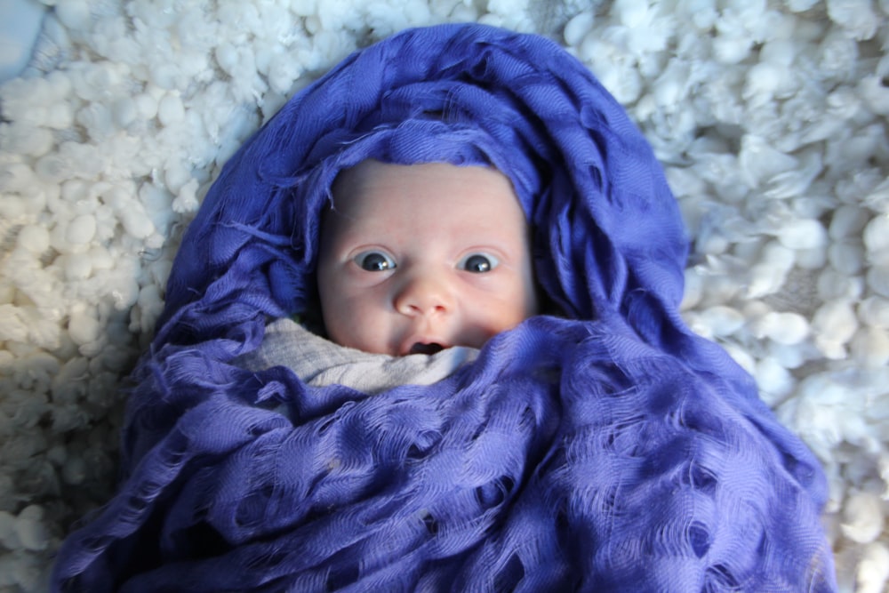 青い毛布の上に横たわる赤ちゃん